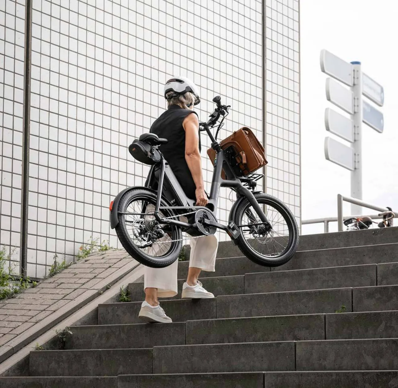 Eine Frau trägt ein i:SY Kompaktrad eine Treppe hoch.