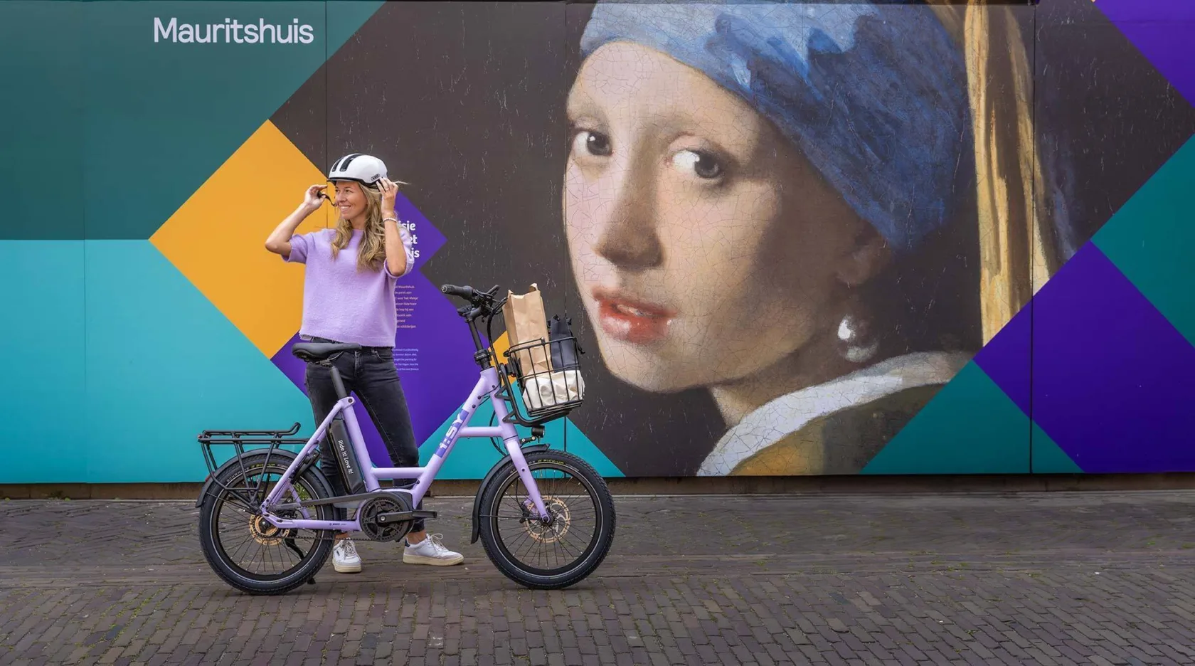 Zwei Männer stehen an ein Geländer gelehnt auf einer Strandpromenade, im Hintergrund Strand und das Meer. Vor ihnen stehend zwei Kompaktfahrräder.